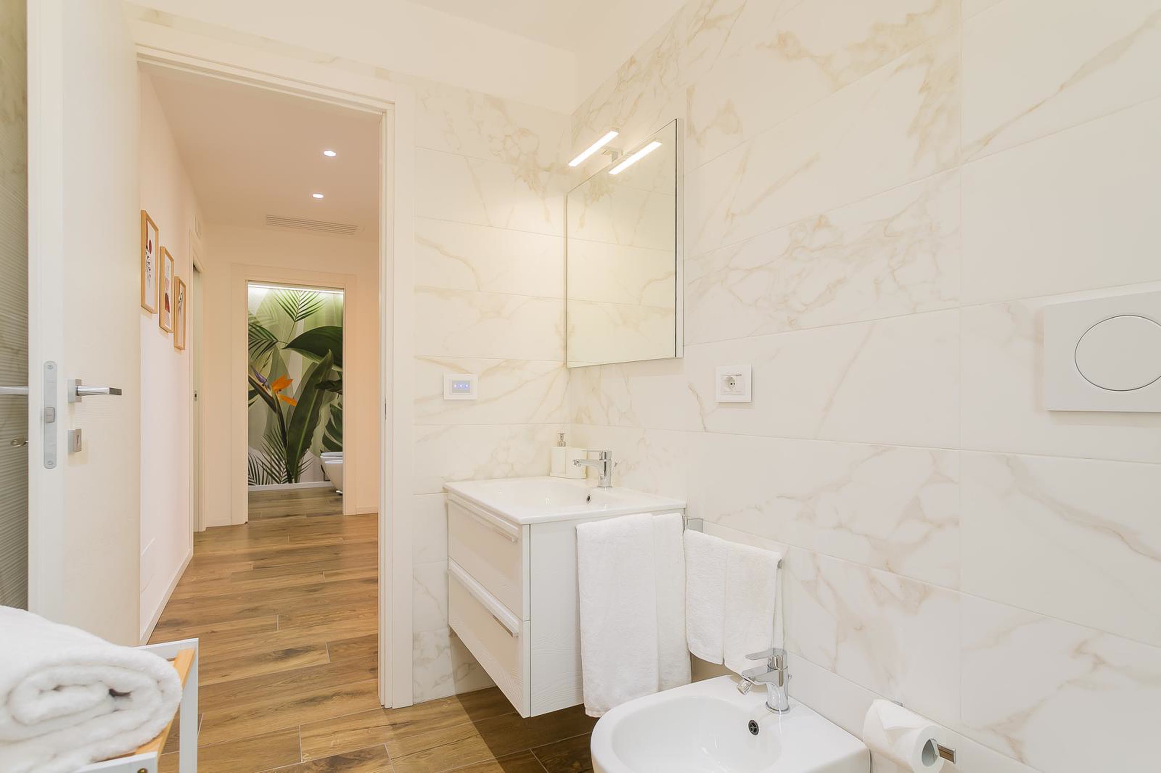 Bagno chiaro con rivestimenti effetto marmo